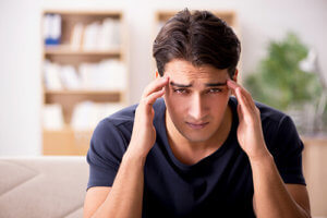 man with headache exhibits alcoholism symptoms